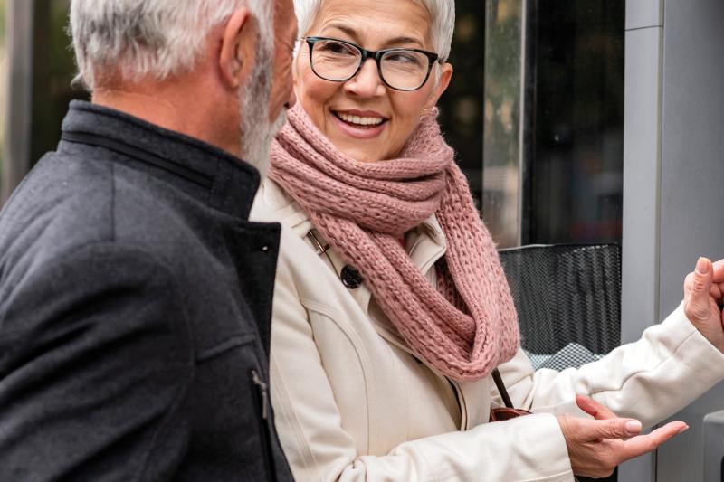 woman and man have a conversation next to an ATM