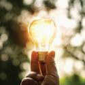 Hand holding lightbulb with outdoors backlight 