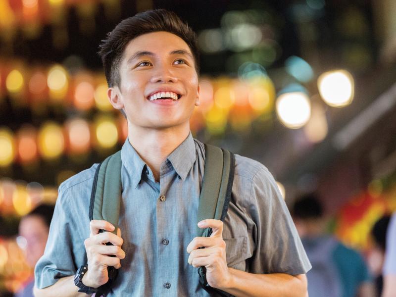 Asian man, smiling. Blurred lights in the background.  