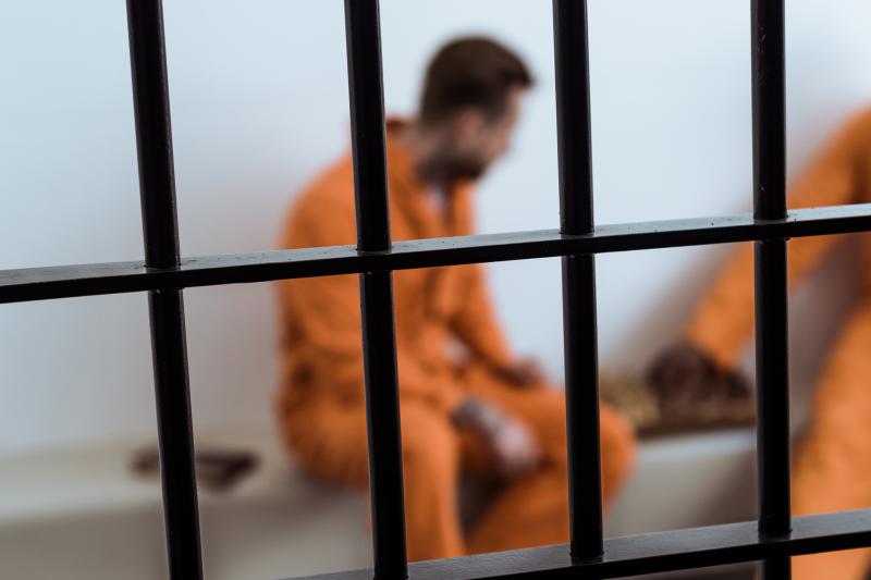 Prisoners in orange jumpsuit playing a game behind bars