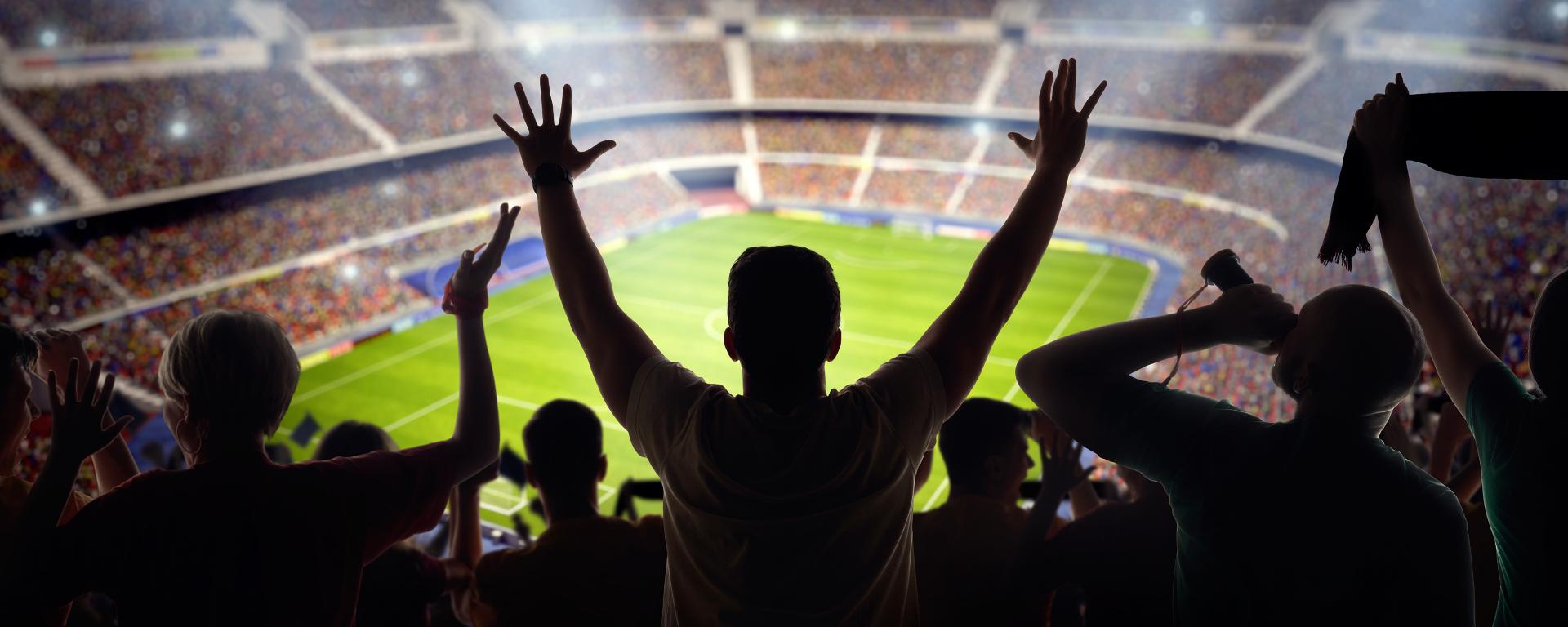 Silhouettes of spectators looking out over a soccer stadium 