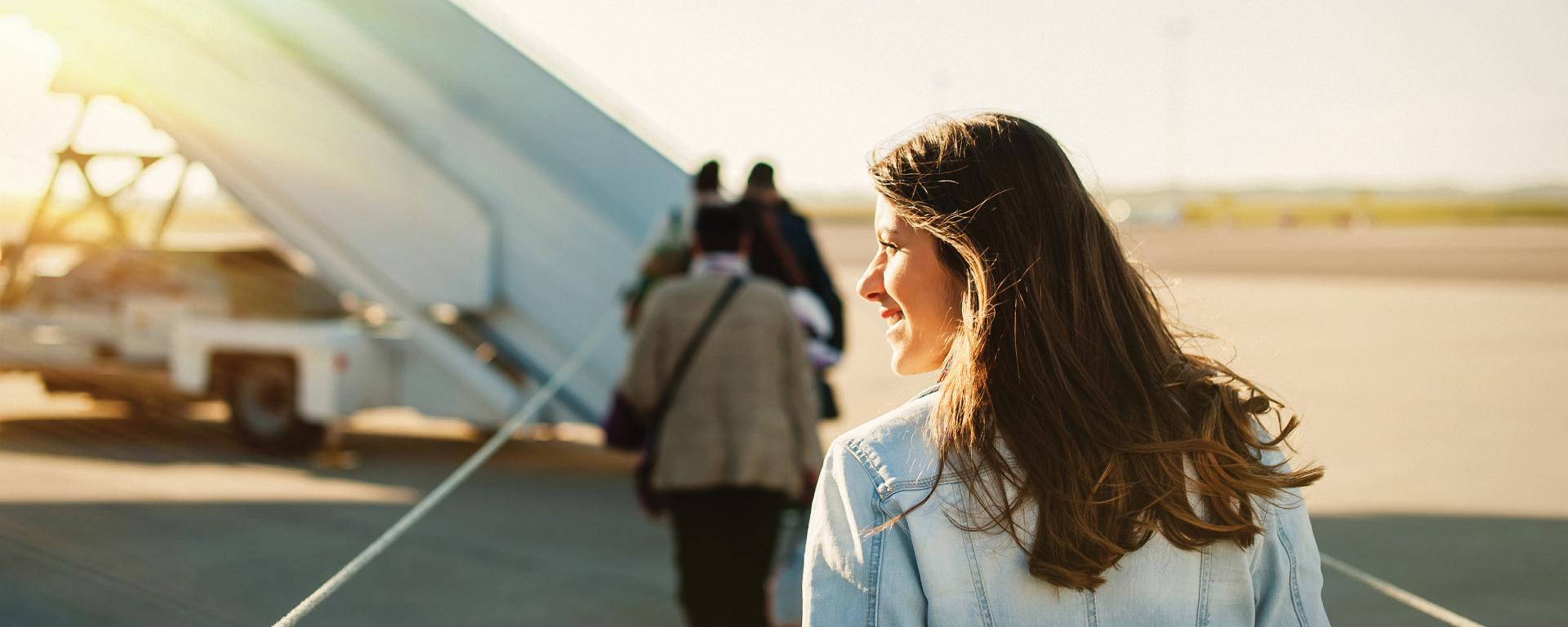 Woman boarding airplane with sunlight in the background